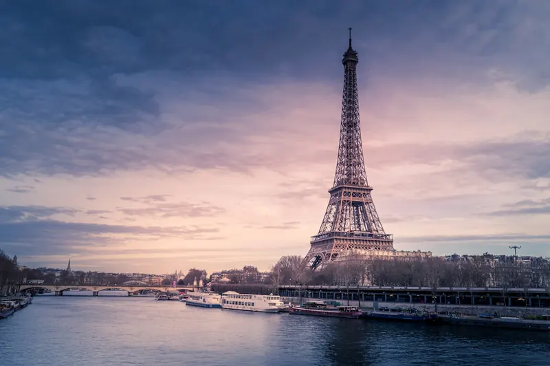Looking up at the ironwork of the Eiffel Tower against a bright sky